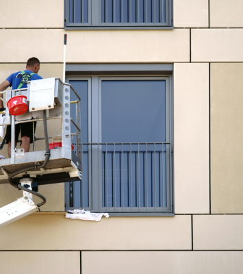 A window cleaner stands on a lift and cleans the windows of a skyscraper.